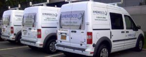 Daytime view of three Ameresco minivans parked outside a building
